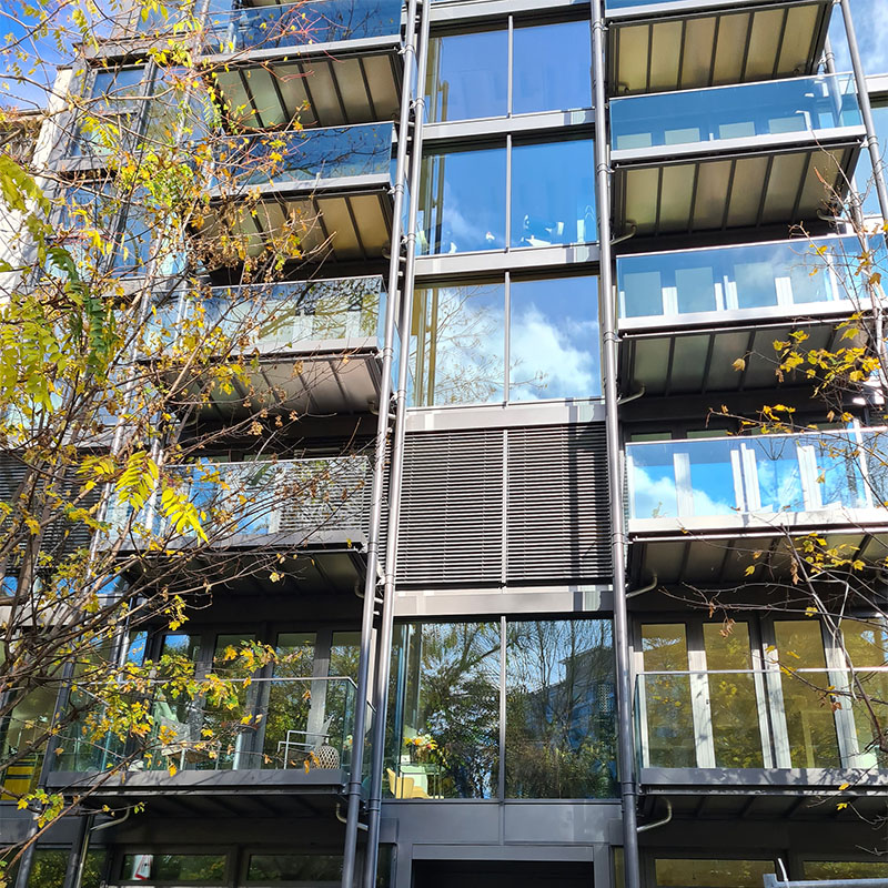 Ein Foto eines mehrstückigen Wohngebäudes mit Glas-Fassade und verglasten Balkonen