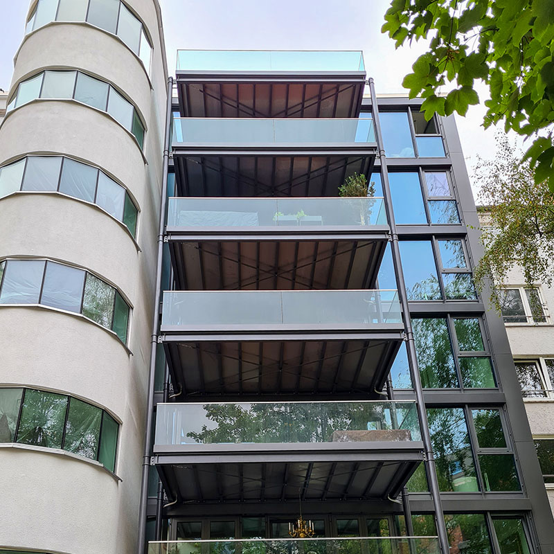 Ein Foto eines mehrstückigen Wohngebäudes mit Glas-Fassade und verglasten Balkonen